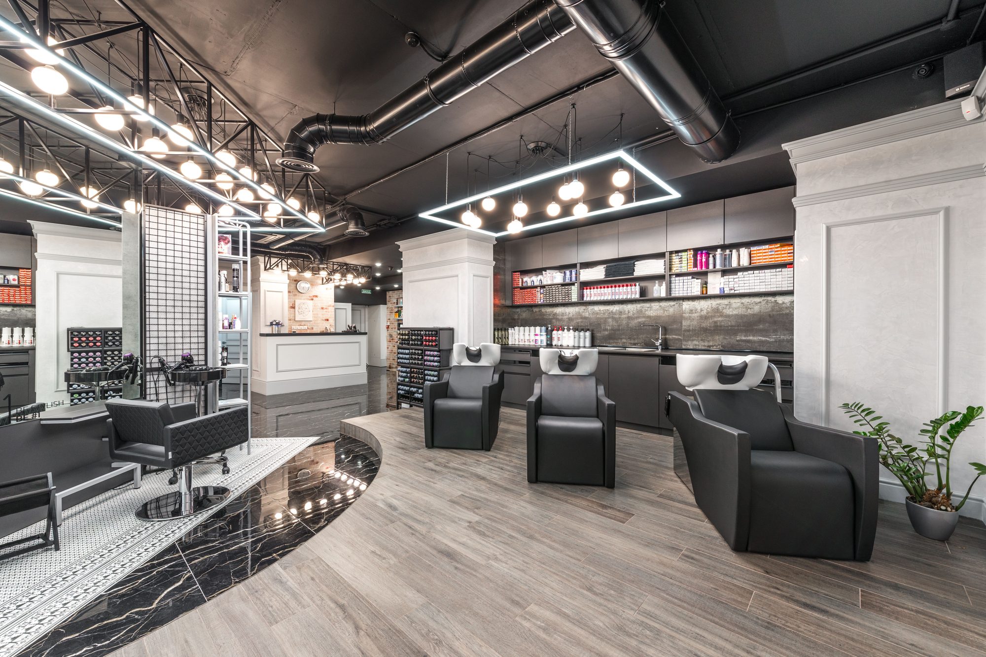 Modern hair studio at Verbena & Clay with black styling chairs, backwash basins, and open shelving of hair products